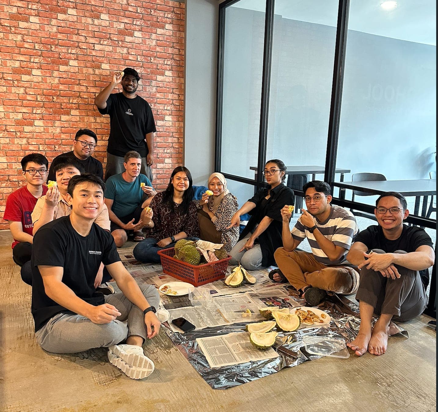 The Sigmaschool team sitting on the floor sharing durian together