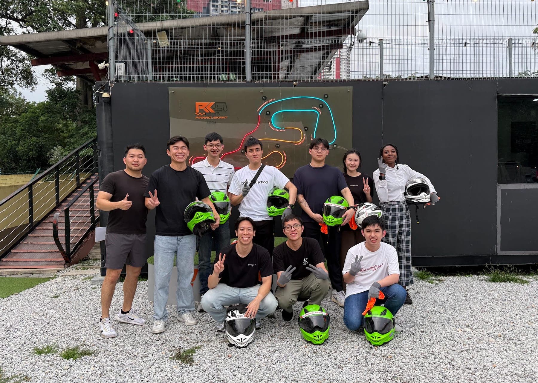 Sigmaschool team holding helmets at the go-kart track